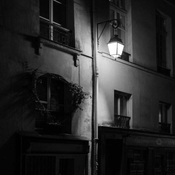 Black and white picture of old city apartments lit by streetlight.